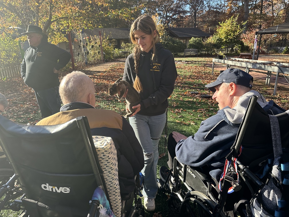 Two Shoreham ICF residents watch at a petting zoo employee shows them a bunny